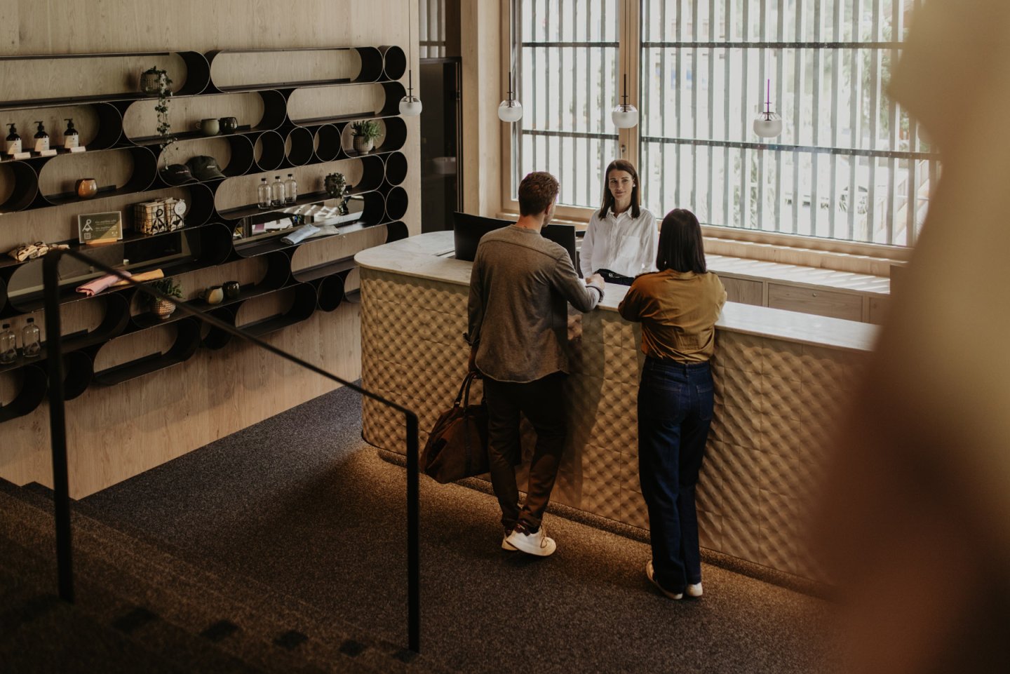 View of the reception with desk, shelving wall and receptionist during check-in