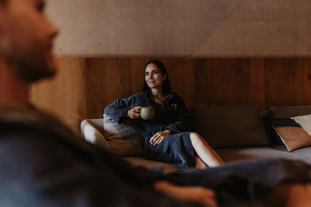 Woman in a bathrobe relaxing with a ceramic cup on the sofa in the relaxation area