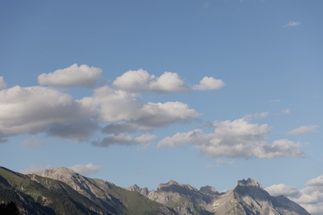 Bergkamm mit zerklüfteten Gipfeln und Schäfchenwolken über grünen Hängen