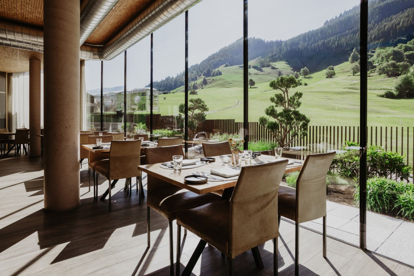 Dining room with laid tables along the window front, view of the green golf course meadow