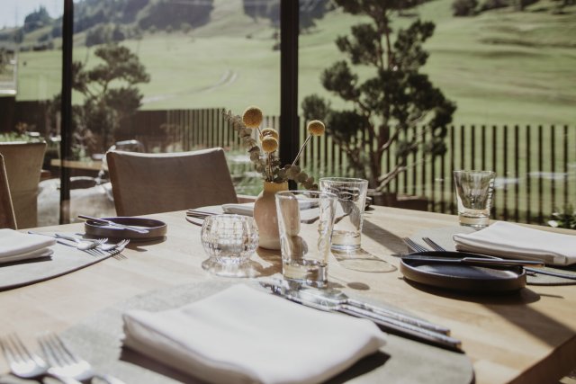 Gedeckter Tisch am Fenster mit Blick auf die grüne Wiese und den Golfplatz